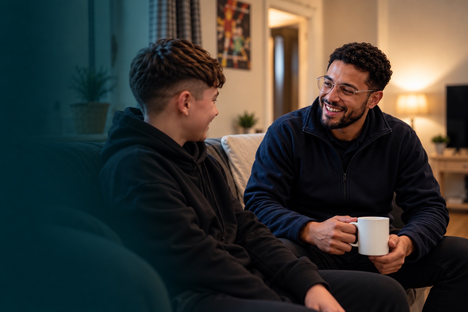 A support worker talking with a young person on a sofa